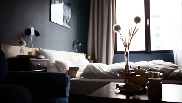 Quarto de hotel iluminado com cama arrumada e janela com vista urbana