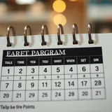 Calendário com marcações de prazo e cartões de fidelidade sobre mesa de trabalho